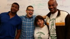 Four team members smiling in front of a whiteboard filled with business strategy notes and diagrams.