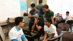 Group of students and instructors collaborating in a classroom during a hands-on workshop or training session.
