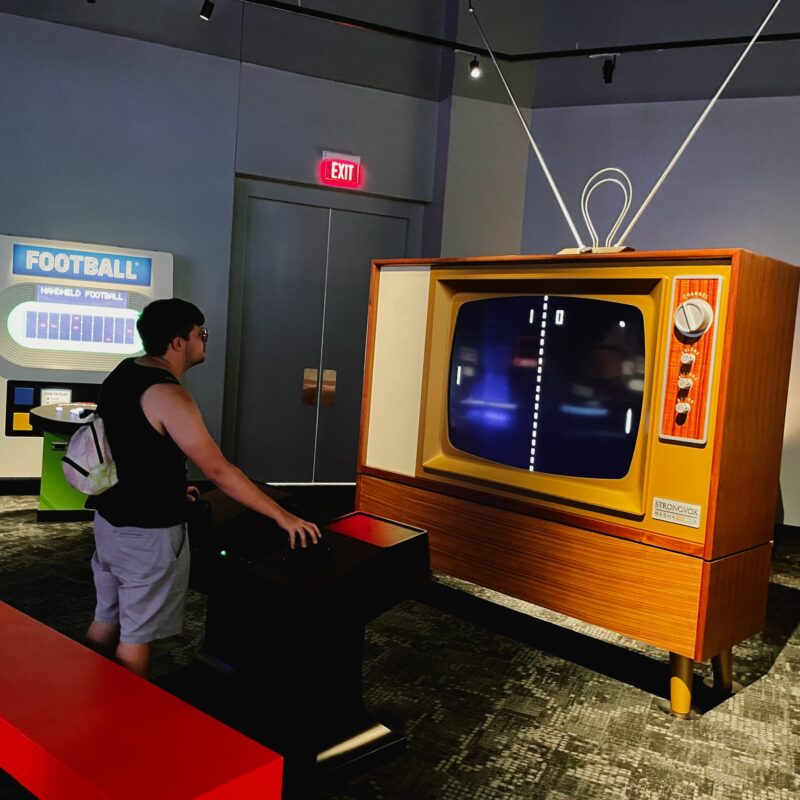 an interactive oversized game of Pong on a faux retro television being played with a large game paddle