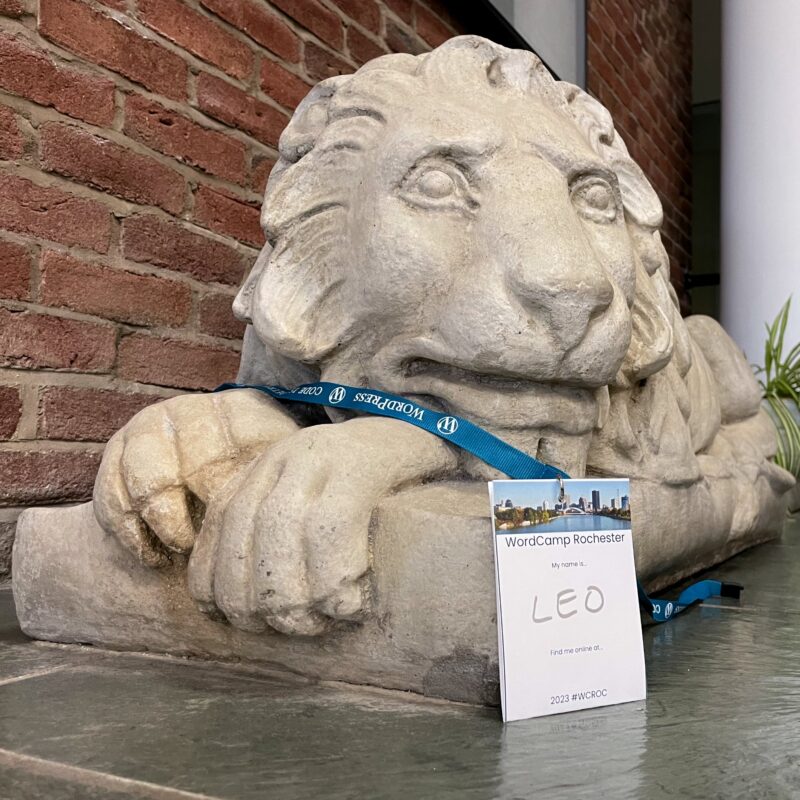 A lion statue with a WordCamp Rochester badge on it that has the name Leo writen