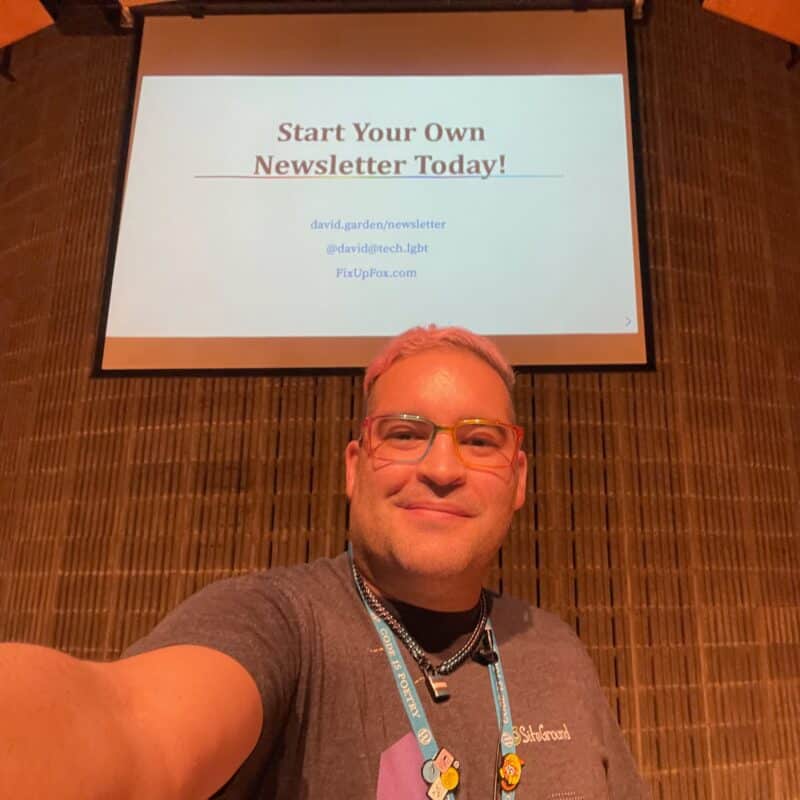 A selfie of david standing in front of a podium and projector at WordCamp Rochester 2023, with the slide for "Start Your Own Newsletter Today!"