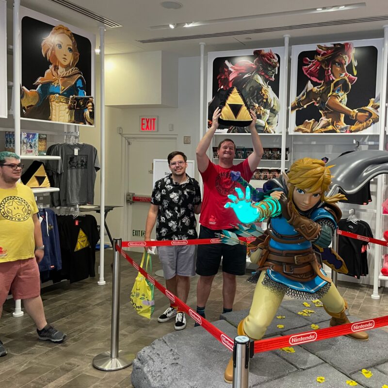 david's partners standing behind a Link statue at the Nintendo World Store in NYC