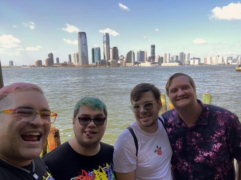 A selfie of david and their partners standing on a pier with Jersey City in the background