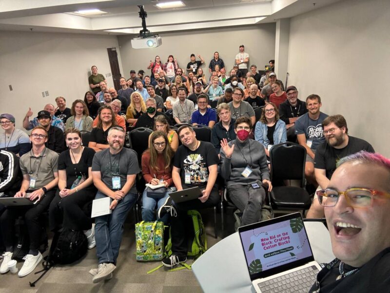 david holding the phone and smiling with a room of people at WordCamp Minneapolis 2024