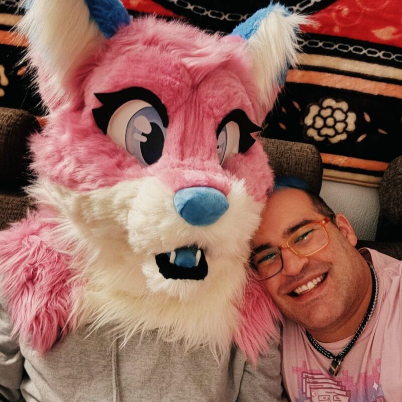 david and Mattie posing together, Mattie wearing her pink and white fox fursuit head