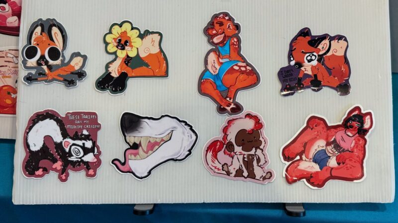 The image shows eight colorful stickers with cartoon animal characters on a white, ridged surface. The top row features a dog in glasses, a fox with a flower, a lounging dog in a blue outfit, and two foxes with a speech bubble saying I don't wanna pay bills. The bottom row includes a skunk with a sign saying These