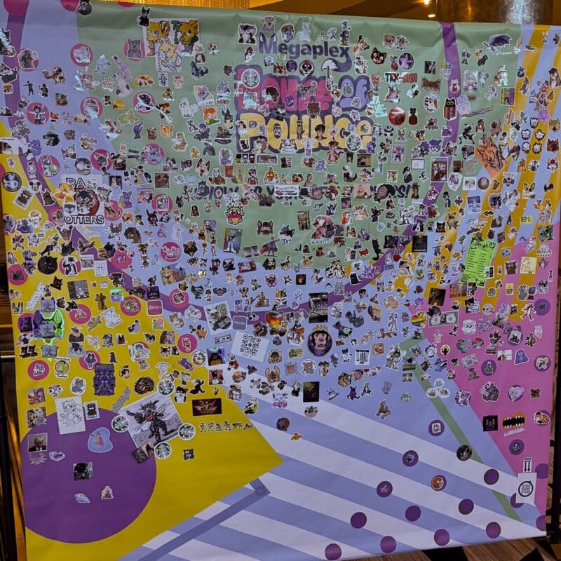 A large, colorful poster filled with numerous stickers is depicted. The background features vibrant swirls of purple, yellow, green, and pink. The stickers are varied, displaying cartoon animals, characters, symbols, and logos. Some text, including Megaplex and other partially obscured words, is visible on the poster. The overall appearance is