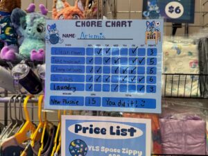 A colorful chore chart labeled Artemis features tasks like cleaning room, taking out trash, and doing dishes with checkmarks across the week. Points are tallied to 22. Reward is a New Plushie with a goal of 15 points, and the note You did it! with a smiley face. The chart