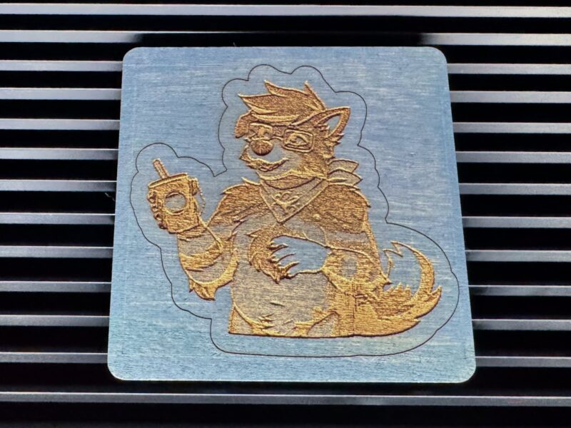A wood cut and engraved drawing of BowieBarks on a piece of blue stained wood