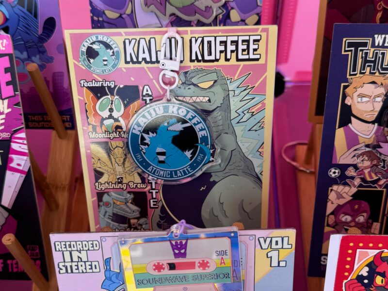 A postcard for Kaiju Koffee, with an acrylic charm of the same in front of it